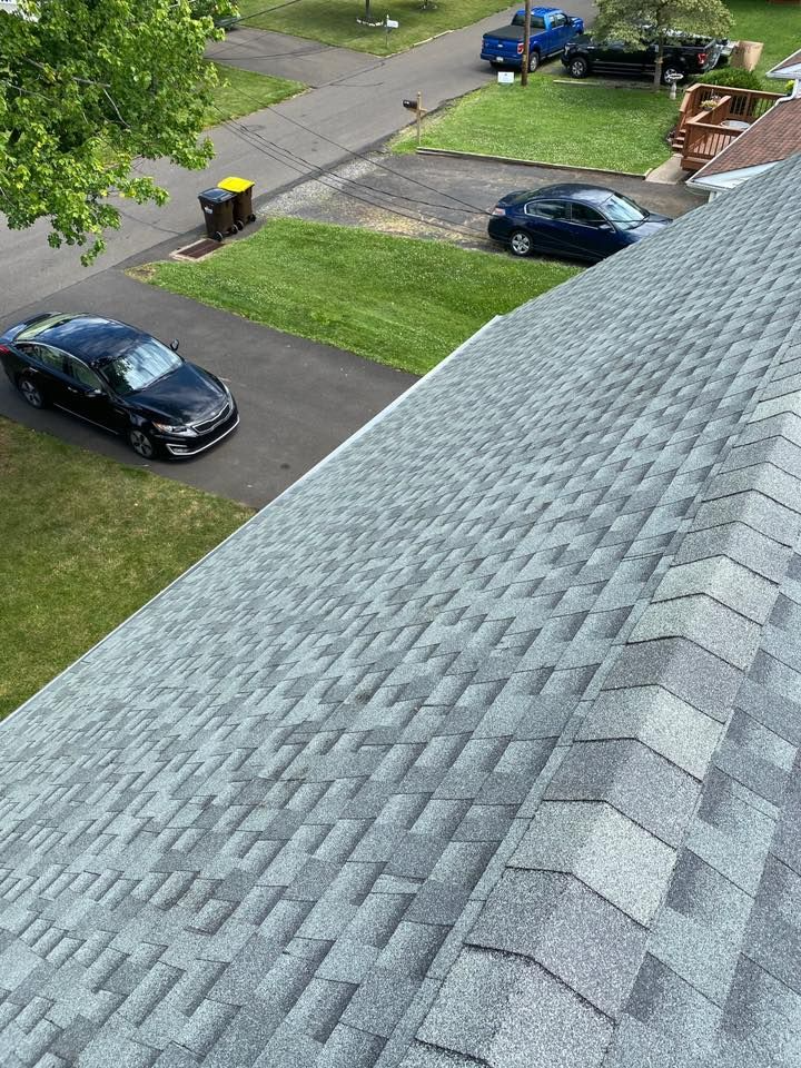 Gray shingle roof, view overlooking a suburban street with parked cars and green lawns.
