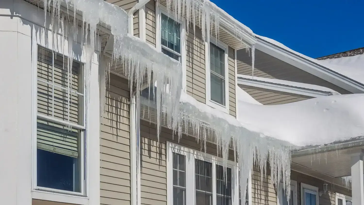 House with large icicles hanging from the roof in a winter setting.