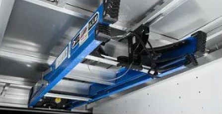 Close-up of black cables and a metal rail inside a gray machine housing, lit by small LED lights