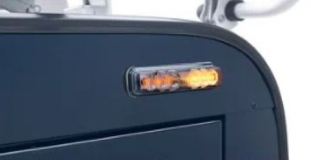 Amber warning light on a dark vehicle roof near a silver roof rack.