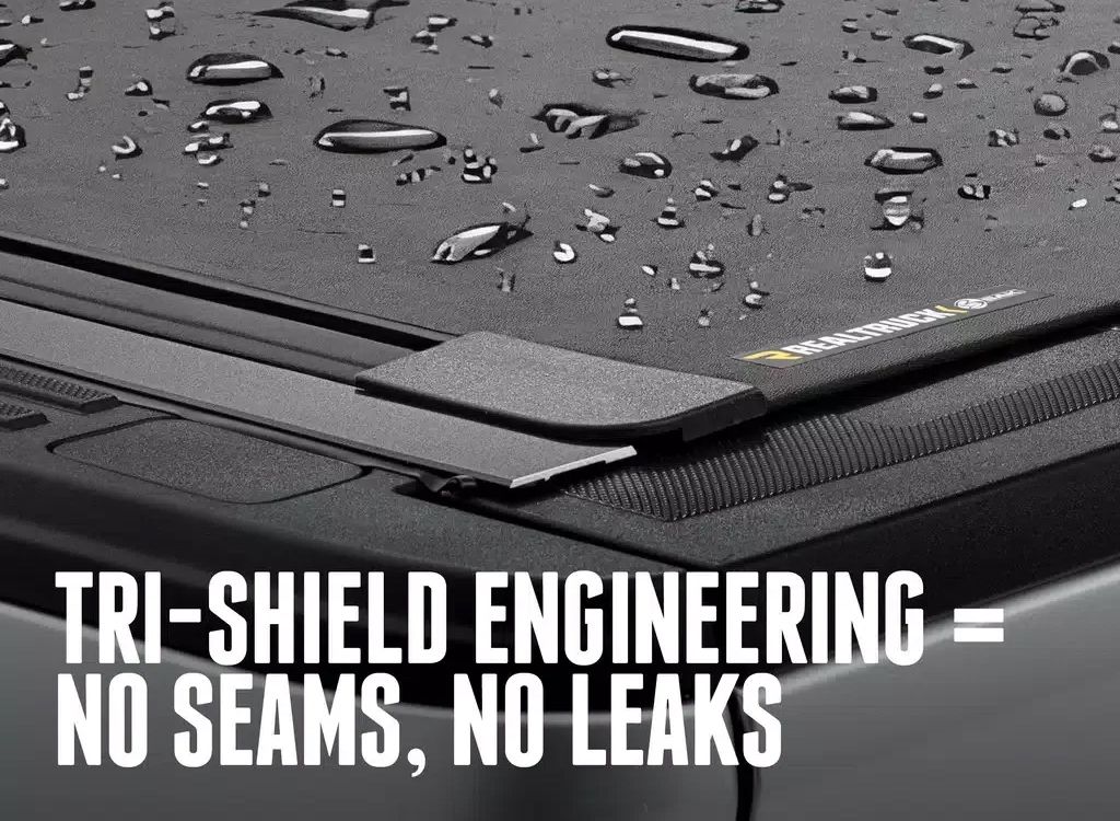 Water droplets on a black laptop with text: TRI-SHIELD ENGINEERING = NO SEAMS, NO LEAKS