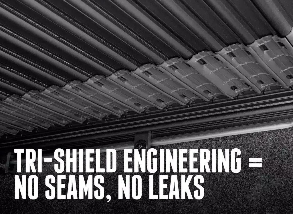 Close-up of a corrugated metal roof with overlay text: TRI-SHIELD ENGINEERING = NO SEAMS, NO LEAKS