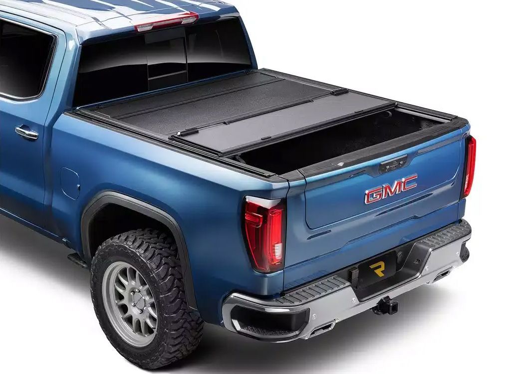 Blue GMC pickup truck with a black bed cover, shown from the rear three-quarter view