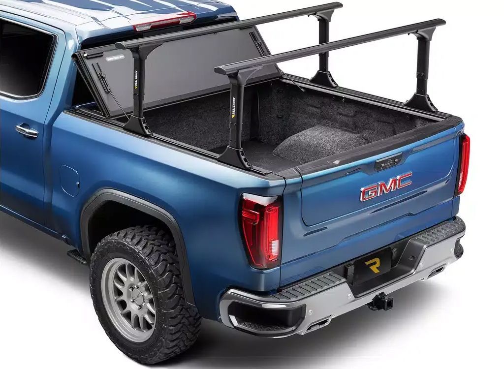 Blue GMC pickup with a black bed rack and cargo bed cover, rear three-quarter view