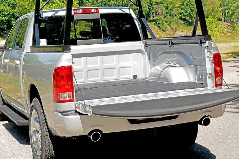Silver pickup truck with tailgate down, showing the empty truck bed and rear lights