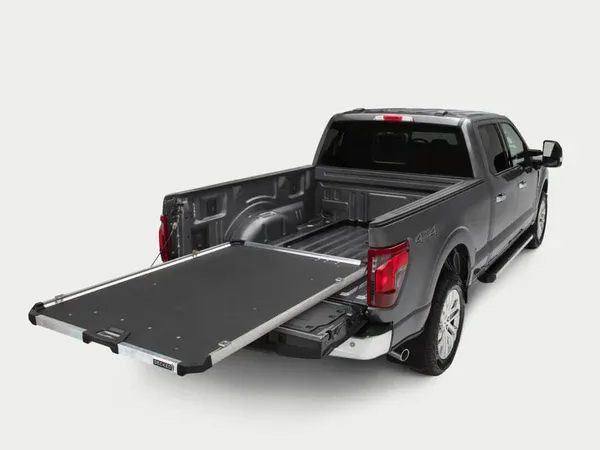 Silver pickup truck with the tailgate down and a folded ramp extending from the bed on a white background