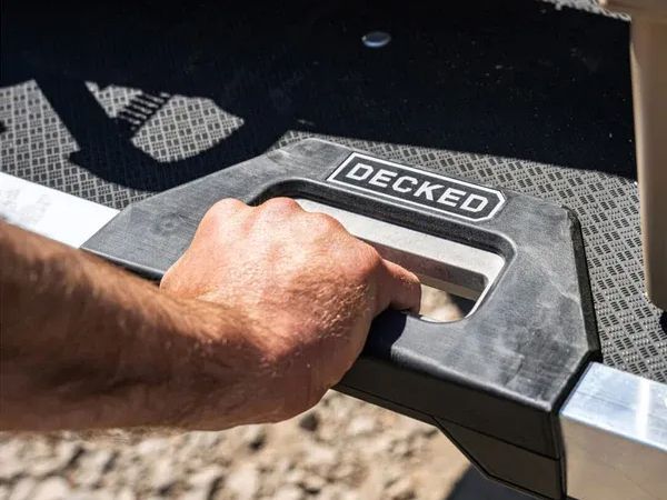 Hand gripping a metal handle on a black DECKED truck bed storage drawer
