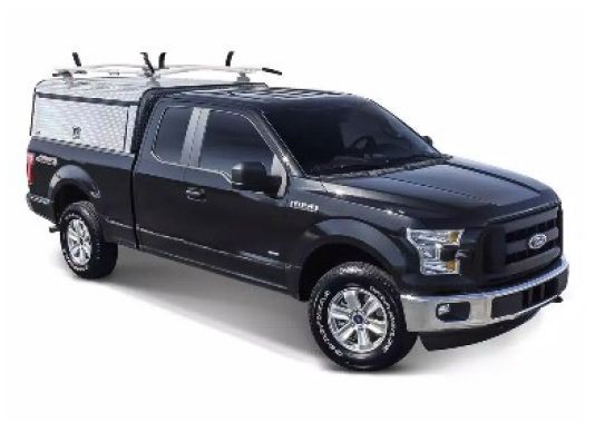 Black Ford pickup truck with a camper shell, angled front view on a white background