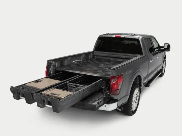 Gray pickup truck with tailgate down, hauling stacked lumber in the bed