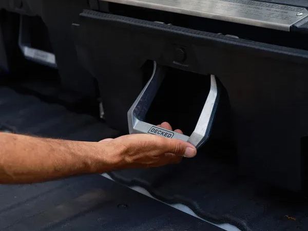 Hand gripping a silver car door handle on a dark vehicle
