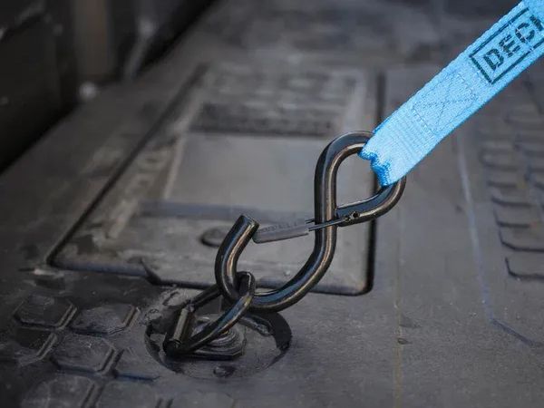 Blue tow strap hooked to a metal hook on a truck bed liner