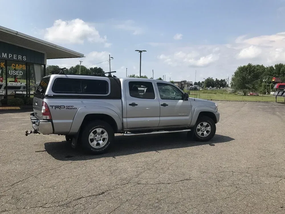 Silver pickup truck parked in a lot beside a restaurant on a sunny day