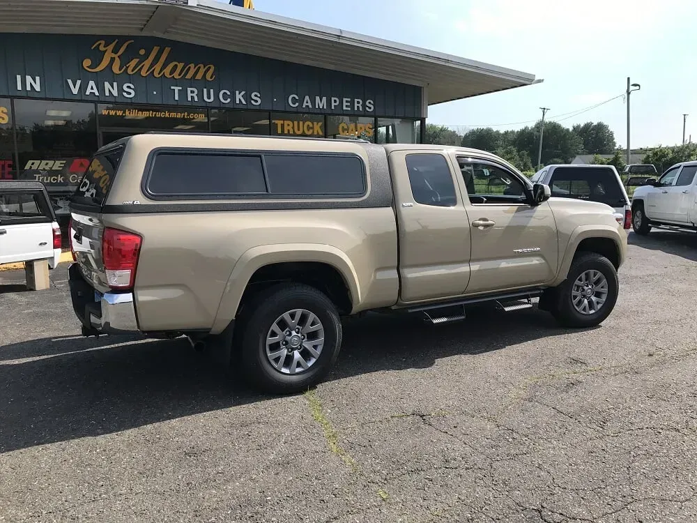 Beige pickup truck parked outside a truck and camper dealership