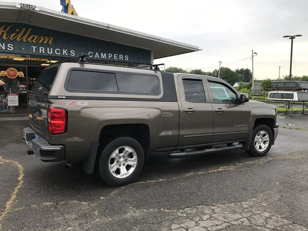 Brown pickup truck parked outside a truck and camper dealership