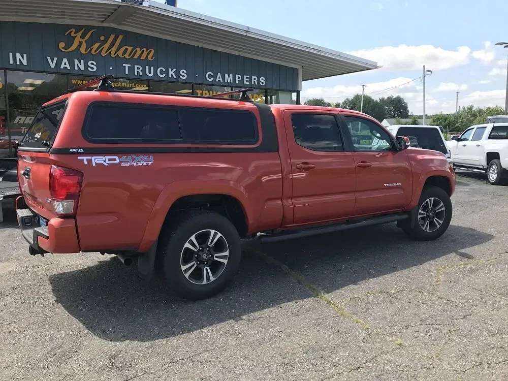 Red pickup truck parked outside a vehicle dealership on a sunny day