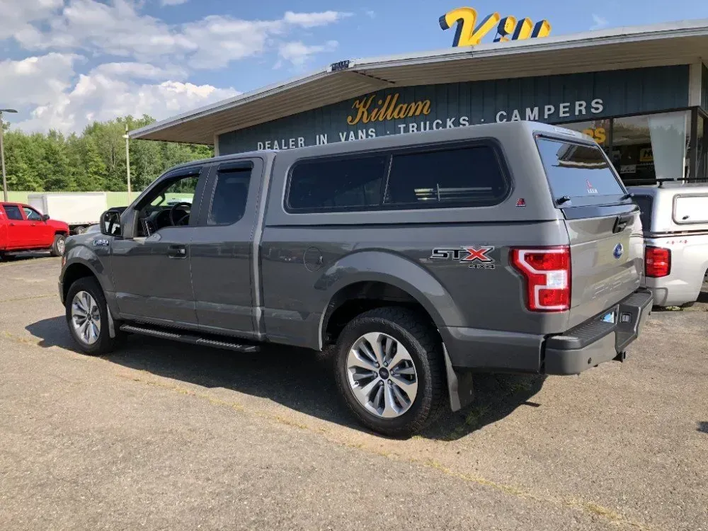 Gray Ford pickup truck parked outside a truck-and-camper dealership