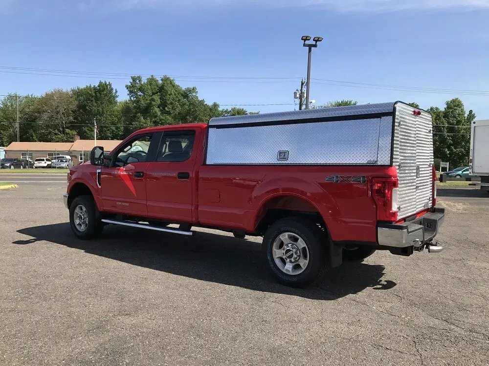 Red pickup truck with a silver utility bed parked in a lot on a sunny day