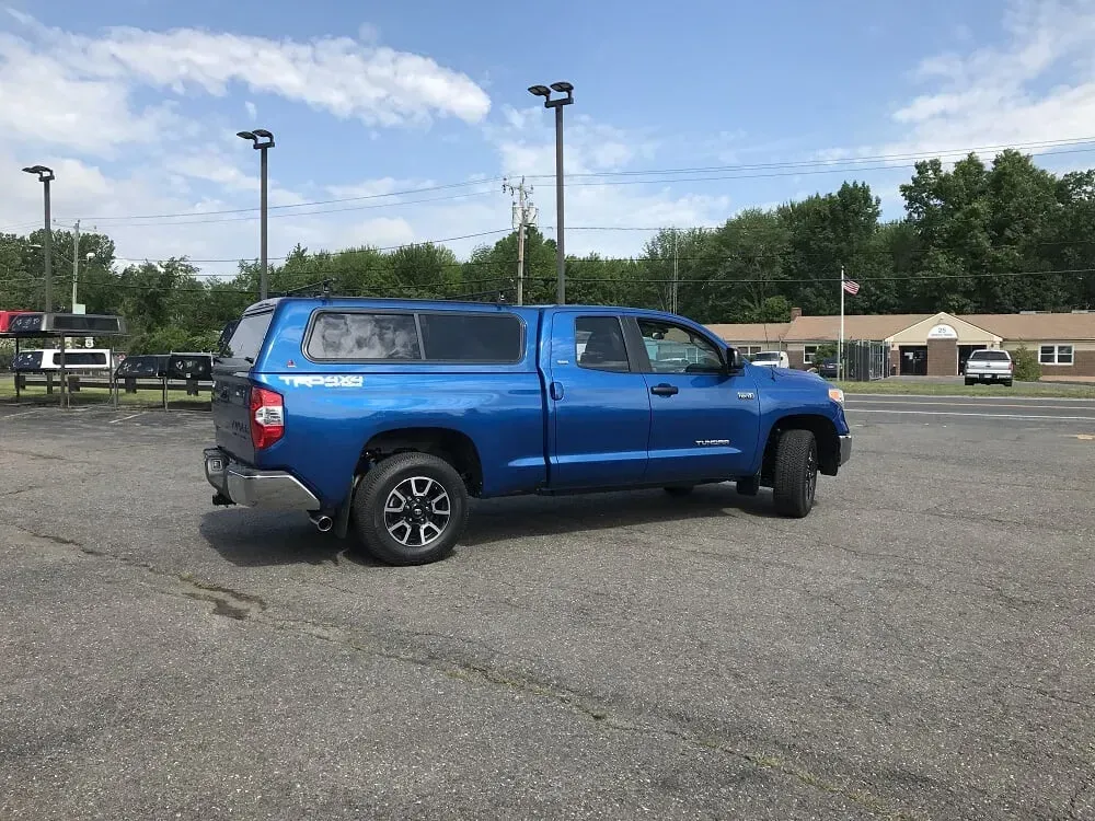 Blue pickup truck parked in an open lot under a partly cloudy sky.