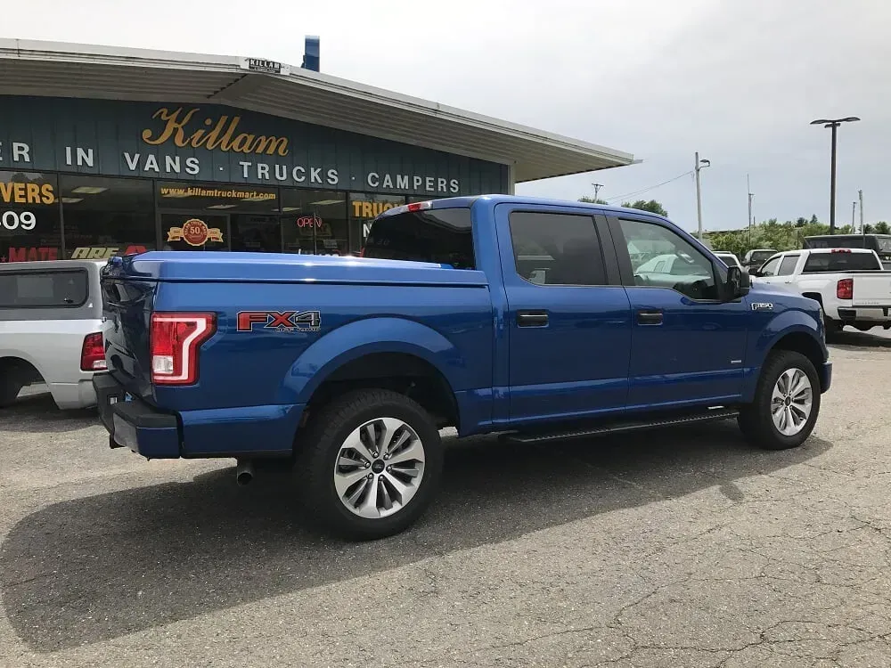 Blue pickup truck parked outside a dealership, side view on a lot