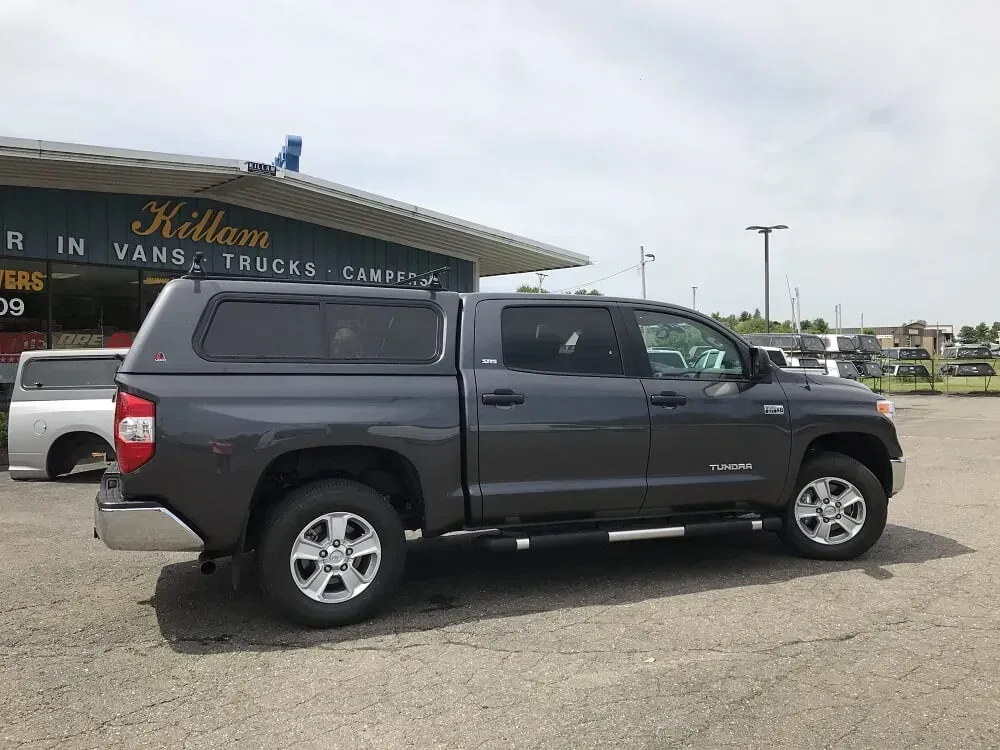 Dark gray pickup truck parked in front of a track and field stadium building