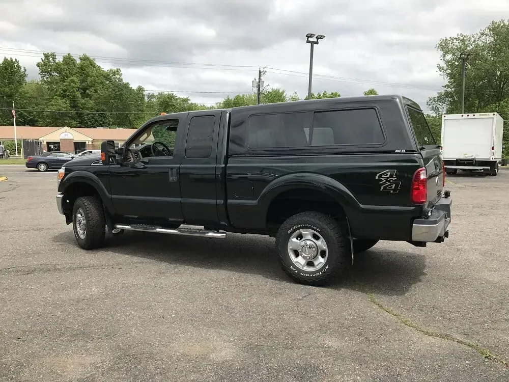 Black pickup truck parked in a lot under cloudy skies, viewed from the side.