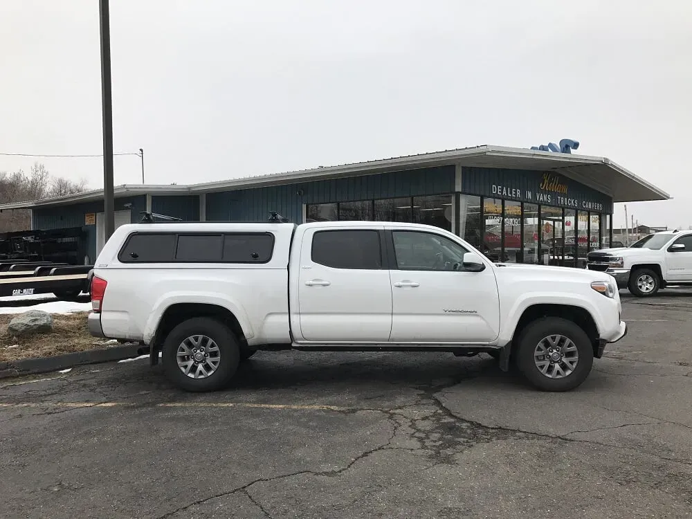 White pickup truck parked outside a dealership on a cloudy day.
