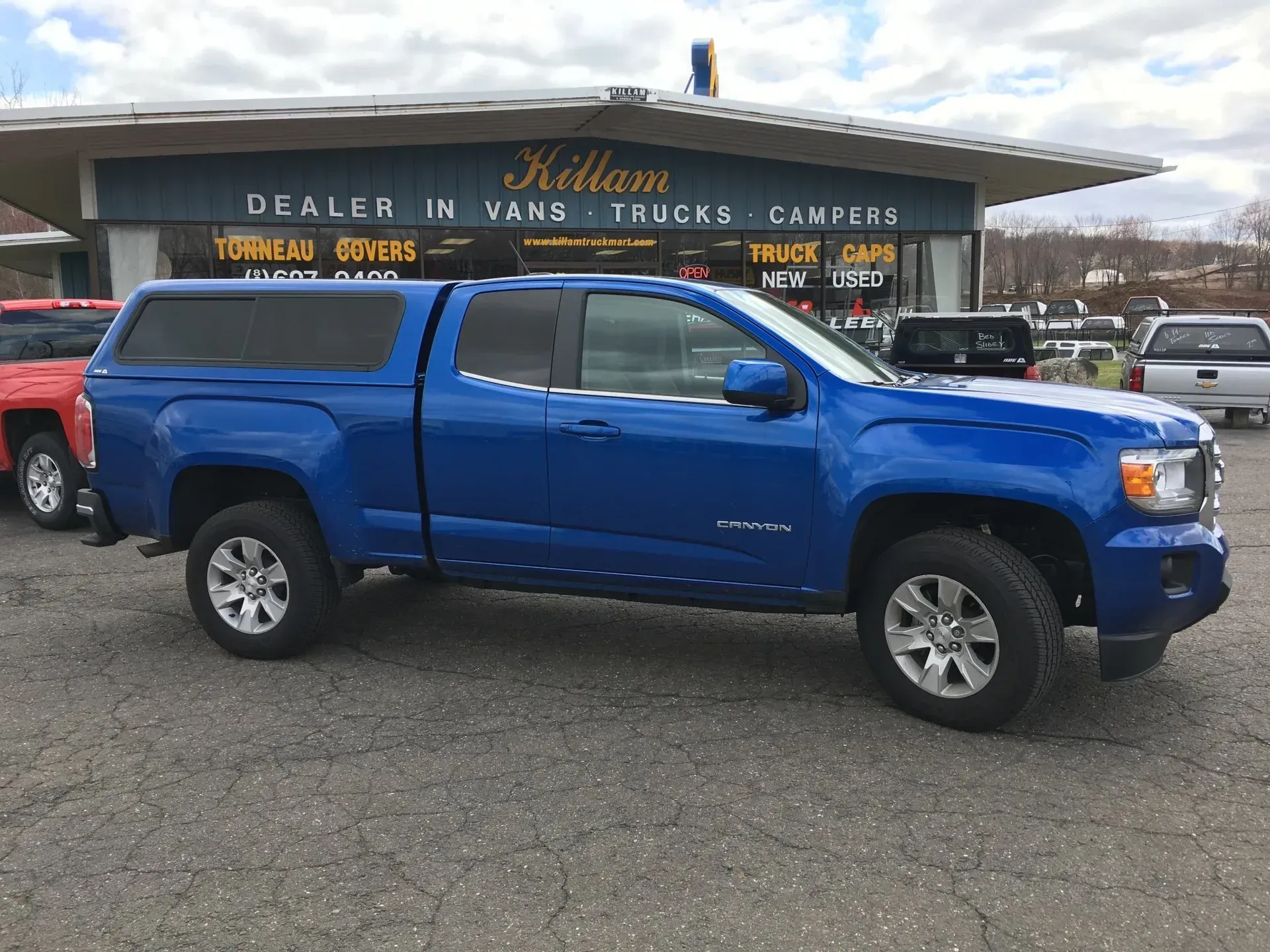 Blue pickup truck parked in front of a truck dealer building