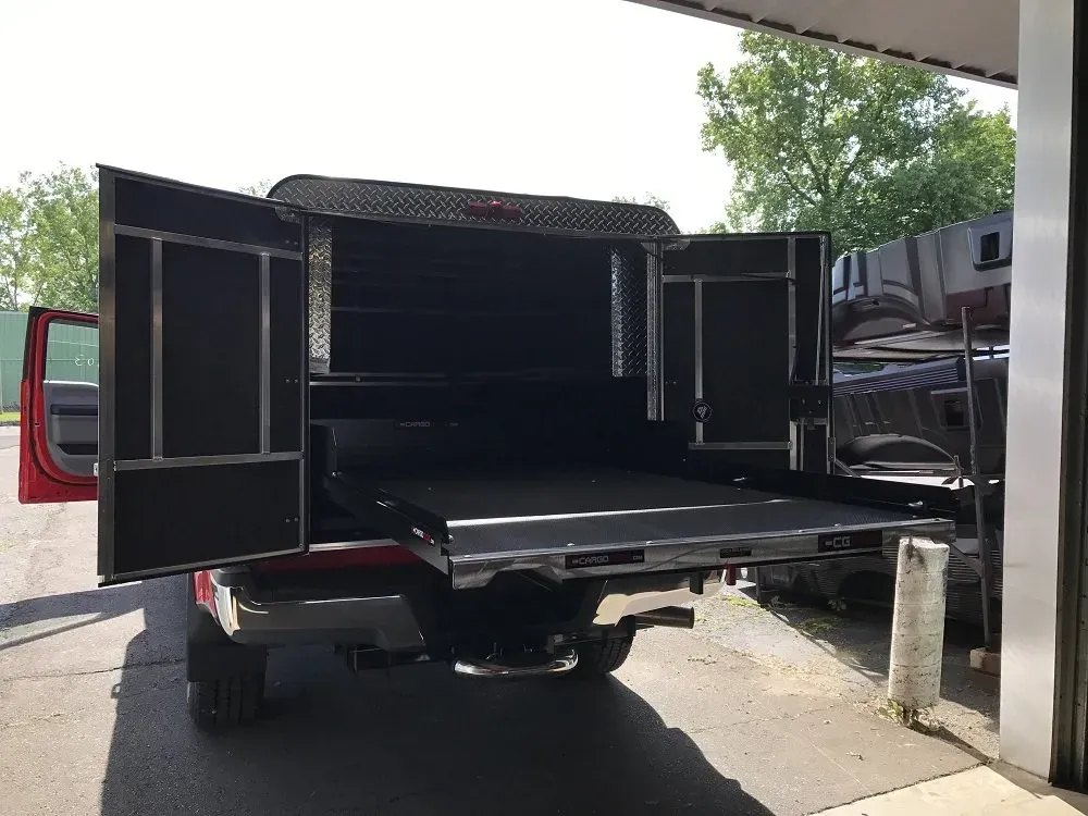 Open cargo trailer with rear doors wide open and a fold-down ramp in a driveway