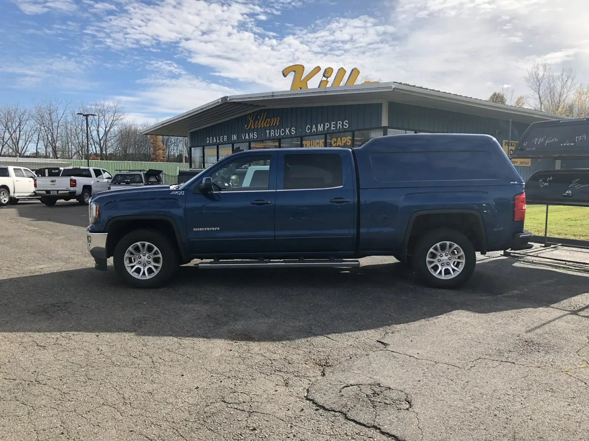 Blue pickup truck parked in front of a K-9 building on a sunny day.