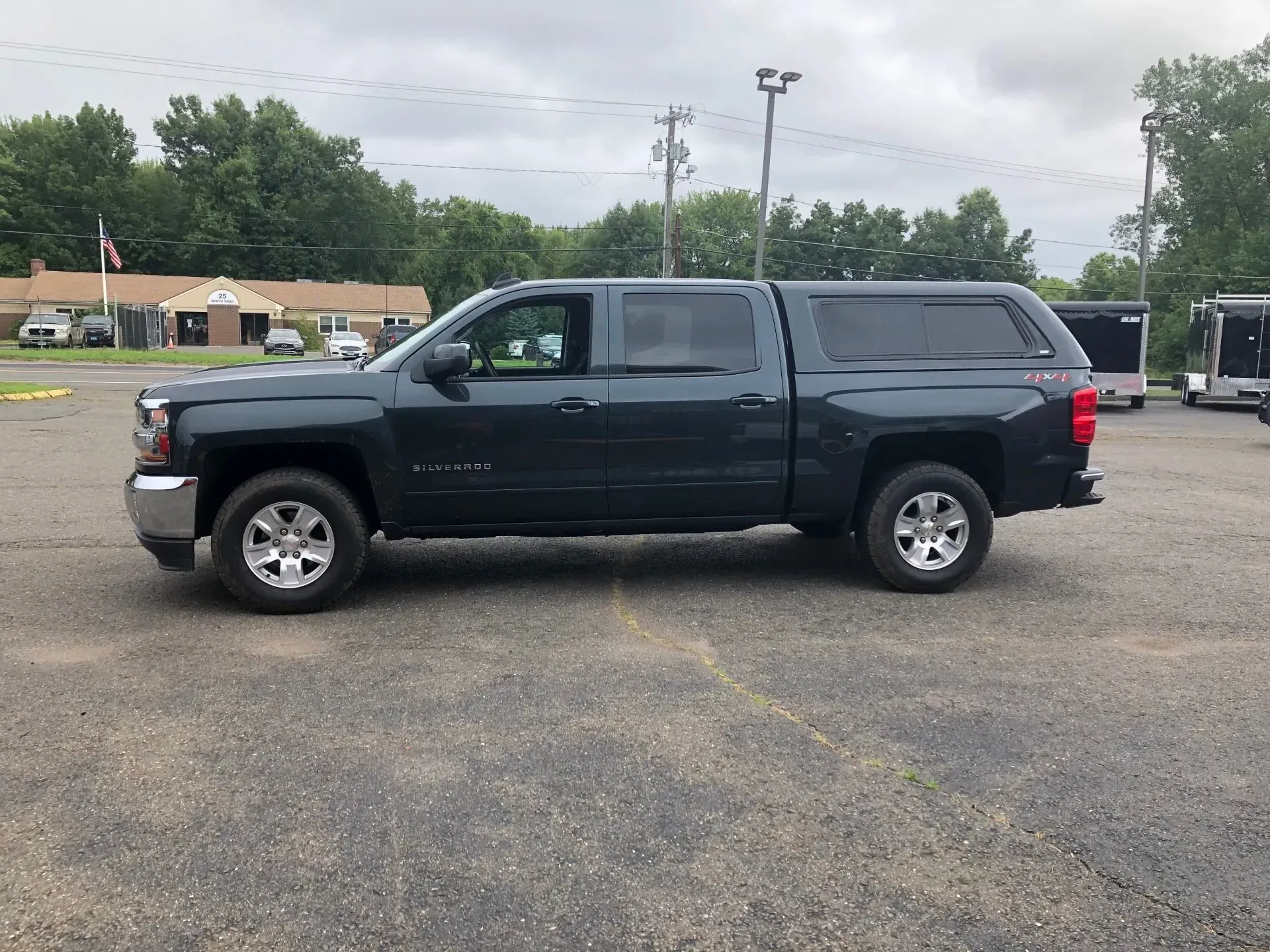 Dark blue pickup truck parked on a gravel lot under a cloudy sky
