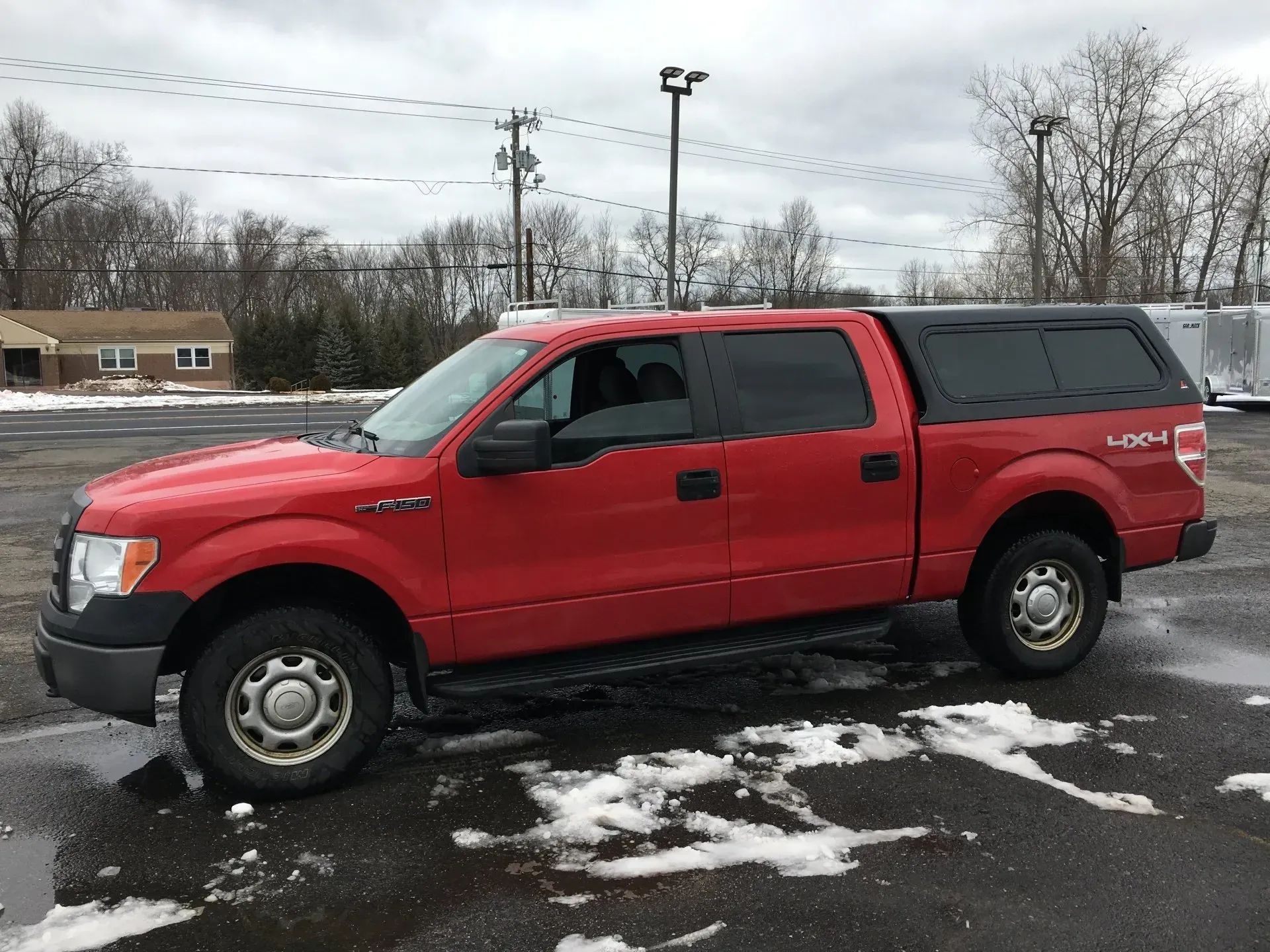 Red pickup truck parked on a snowy lot under a gray sky.