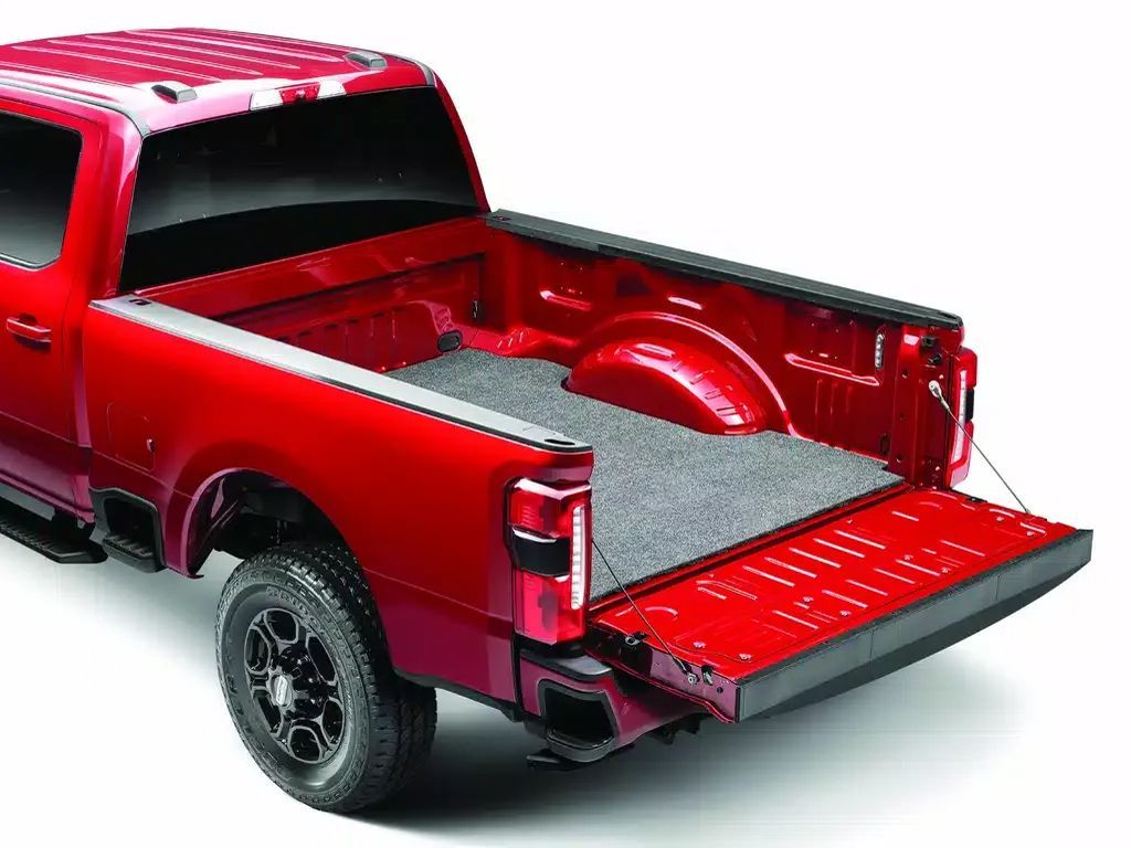 Red pickup truck with open tailgate, showing the empty red bed and black wheels on a white background