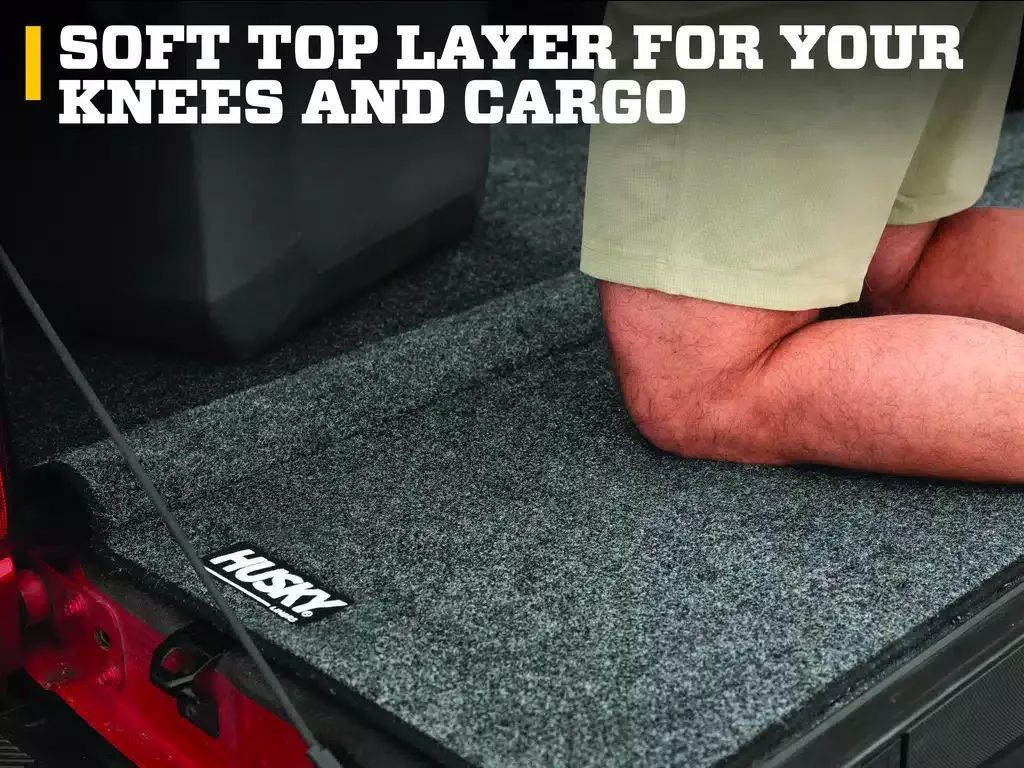 Truck bed mat with text soft top layer for your knees and cargo, showing a person kneeling inside the truck bed