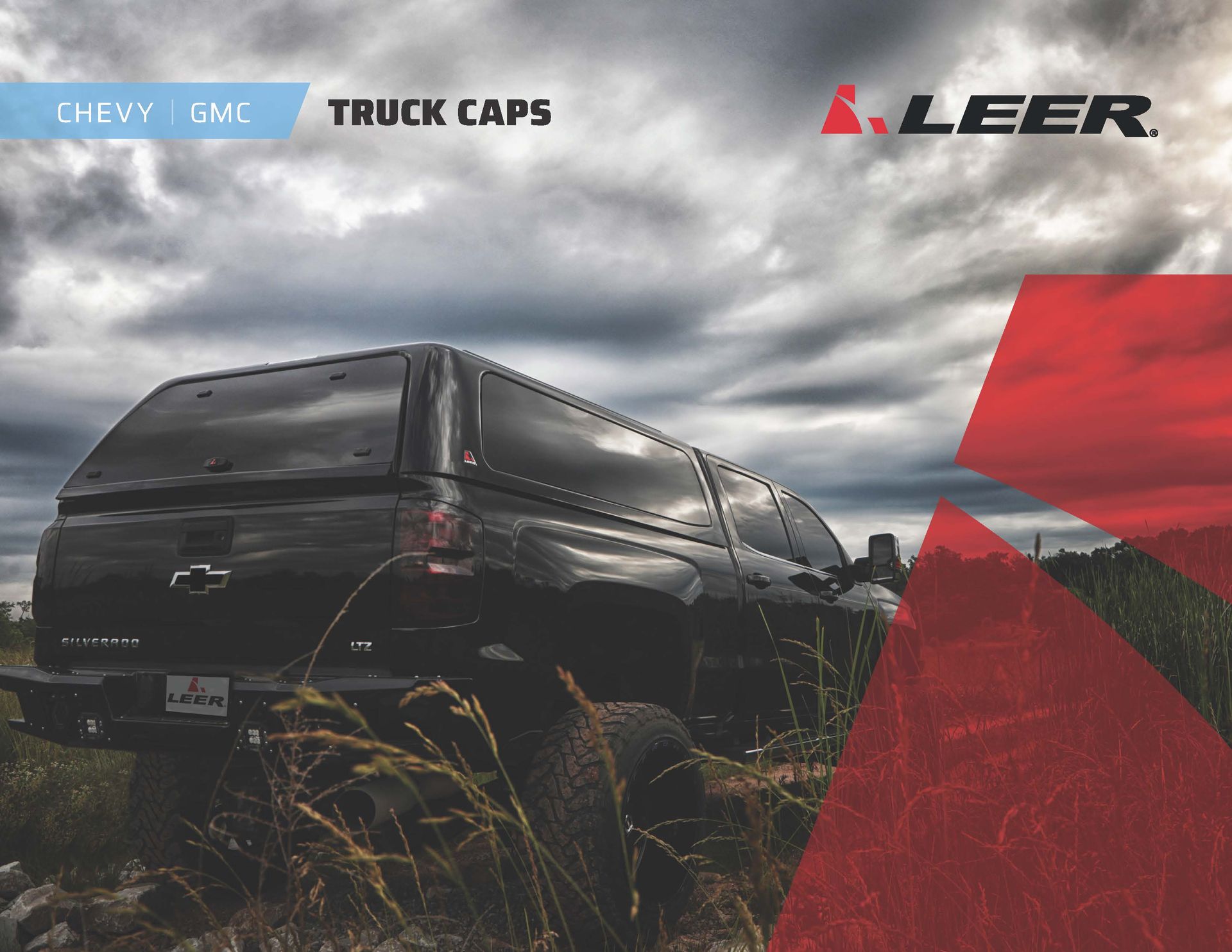 Black Chevrolet Silverado in tall grass under cloudy sky, with LEER truck cap branding.