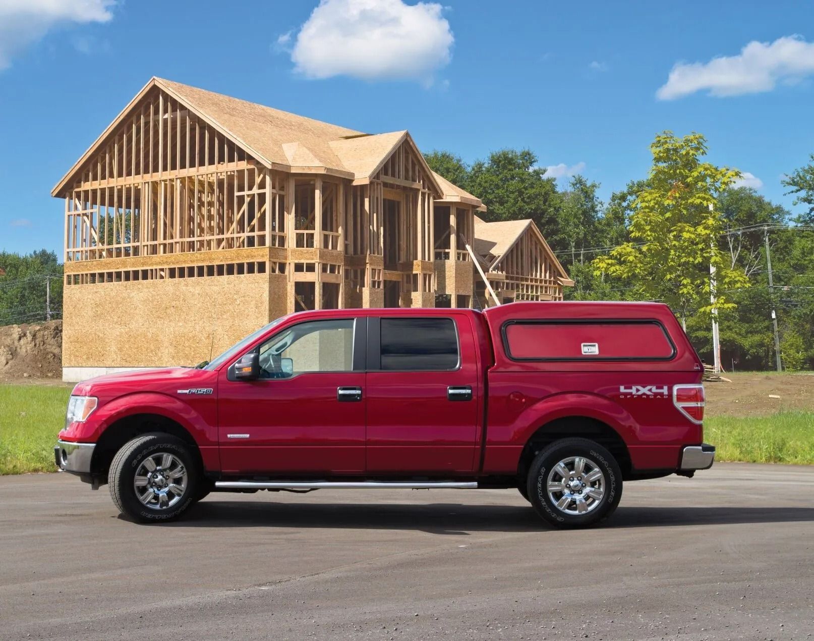Red pickup truck parked beside a house under construction on a sunny day