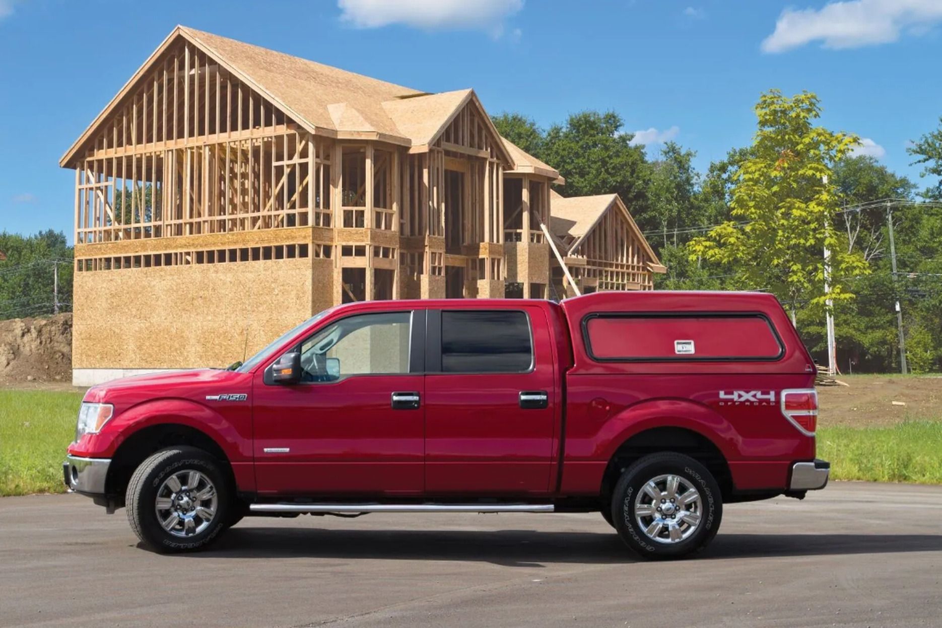 Red pickup truck parked beside a house under construction on a sunny day