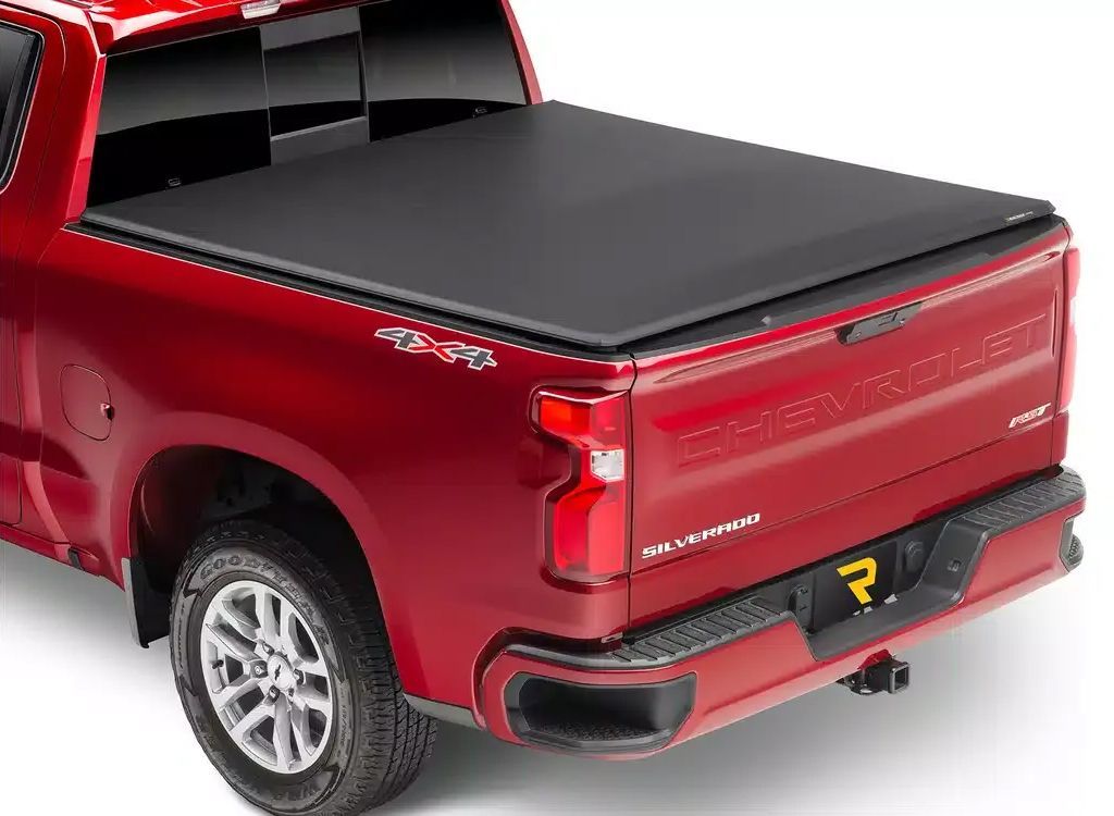 Red pickup truck with a black tonneau cover, rear three-quarter view