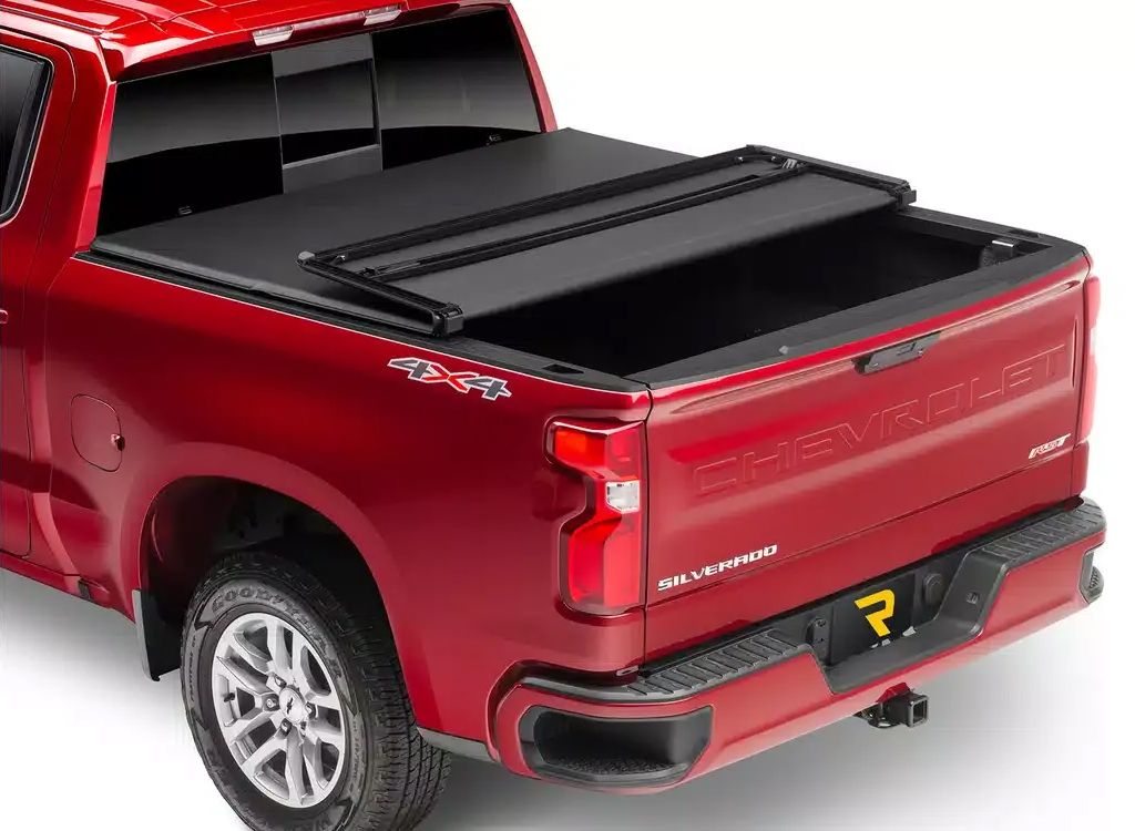 Red pickup truck with a black folding tonneau cover over the bed