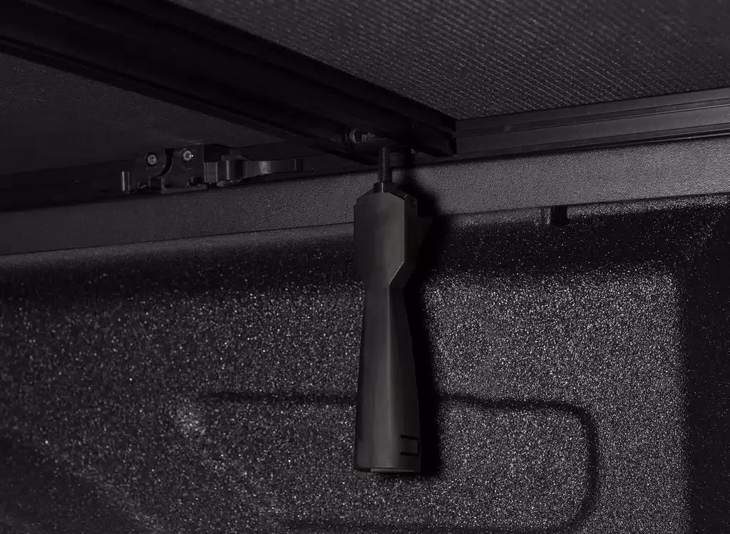 Black cylindrical object mounted under a dark textured surface, viewed from below.