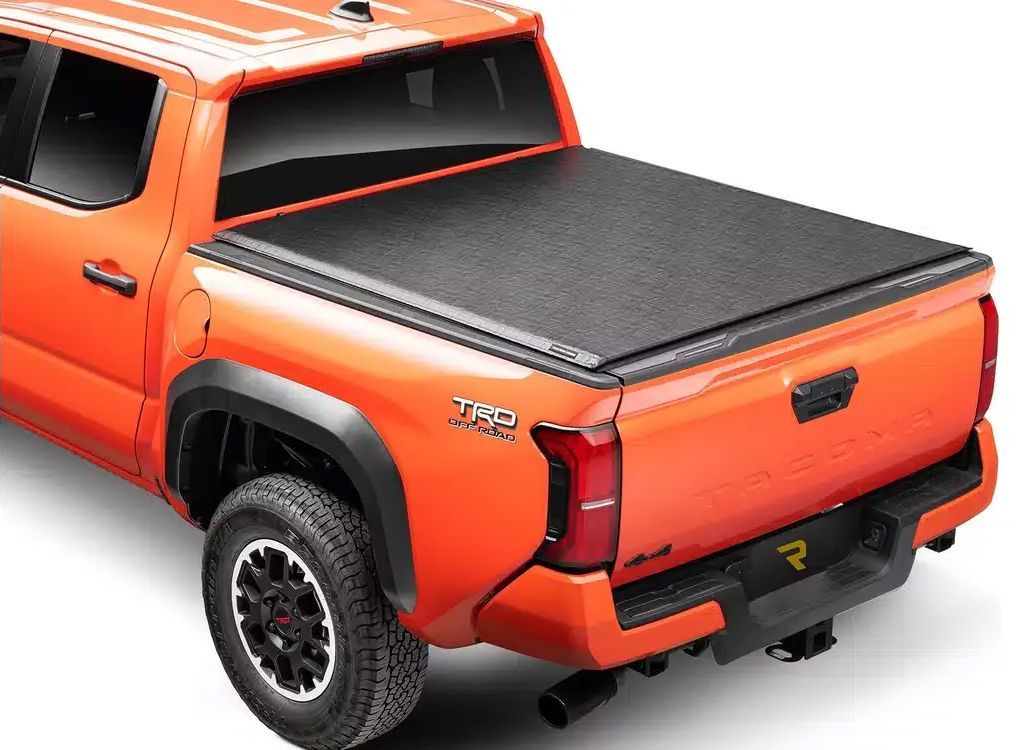 Orange pickup truck with a black hard tonneau cover on the bed, rear three-quarter view