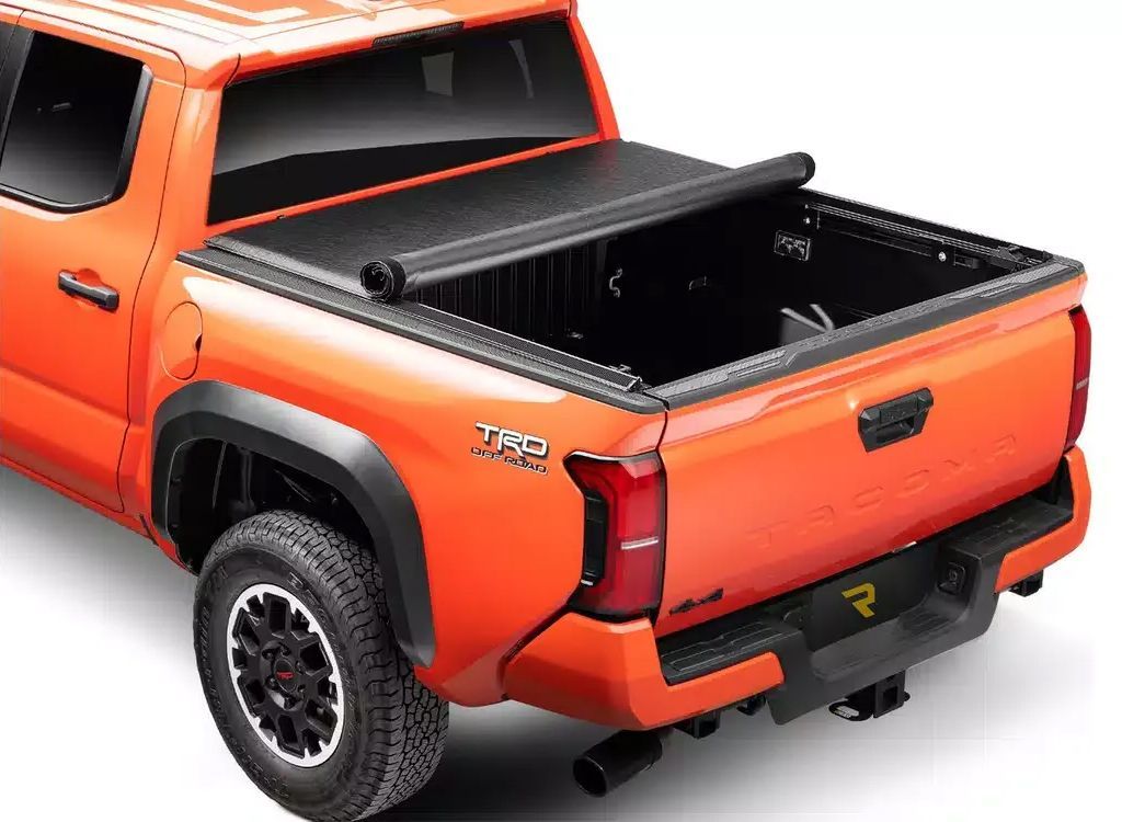 Orange pickup truck with black trim and an open bed, rear three-quarter view