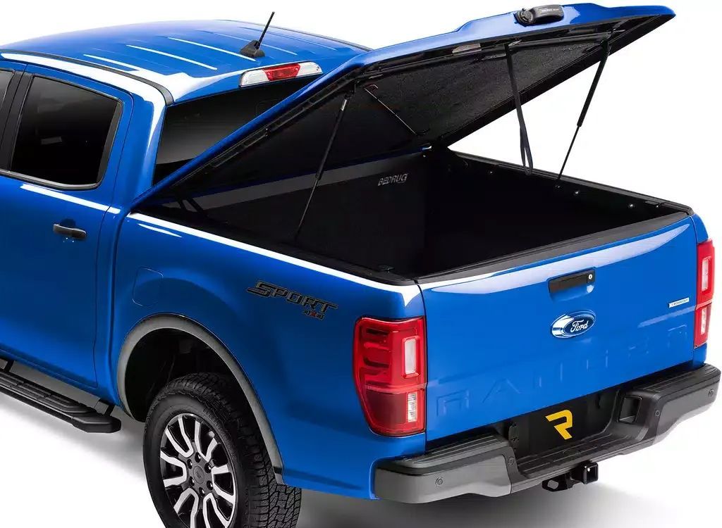 Blue pickup truck with hard tonneau cover open, showing the bed.