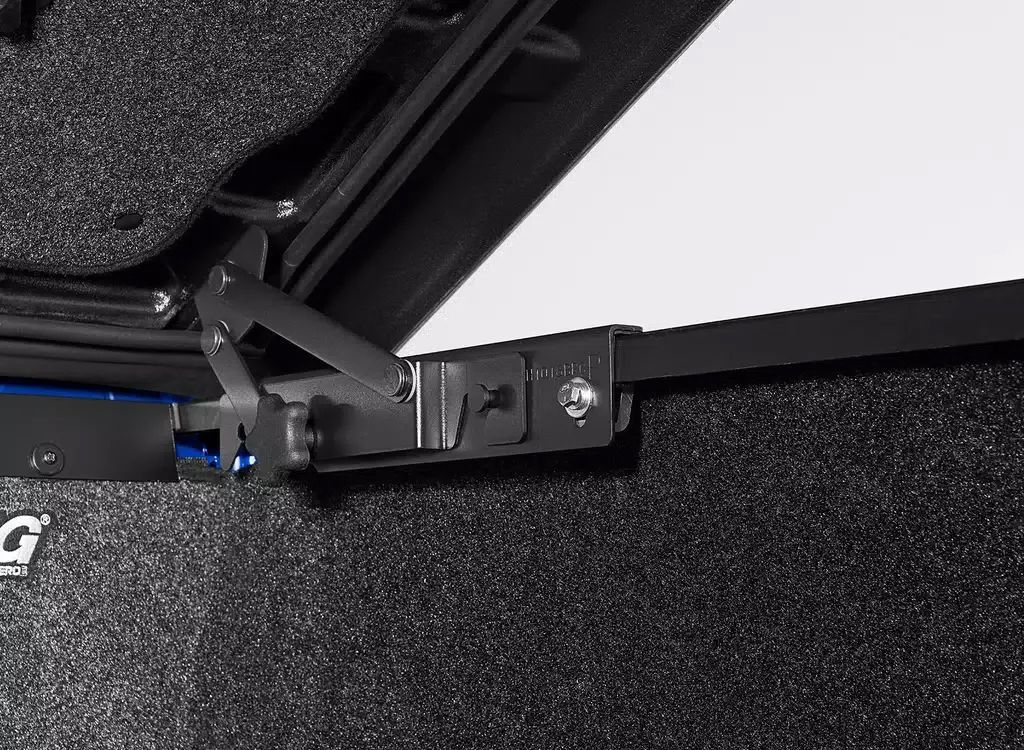 Close-up of a black hinge and mounting bracket on a textured black surface.