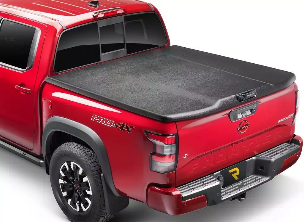 Red pickup truck with black tonneau cover, shown from the rear side.