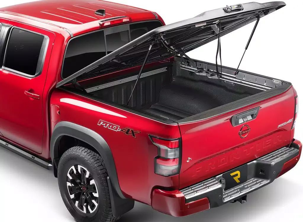 Red pickup truck with a black open tonneau cover over the bed, rear three-quarter view