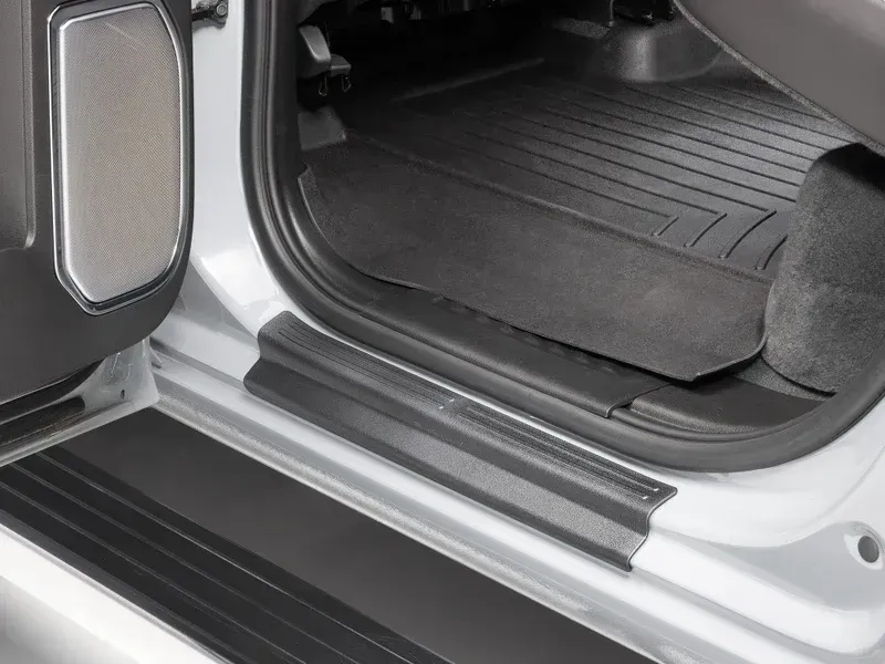 Car door sill and rear cargo area with black protective mats in a silver vehicle