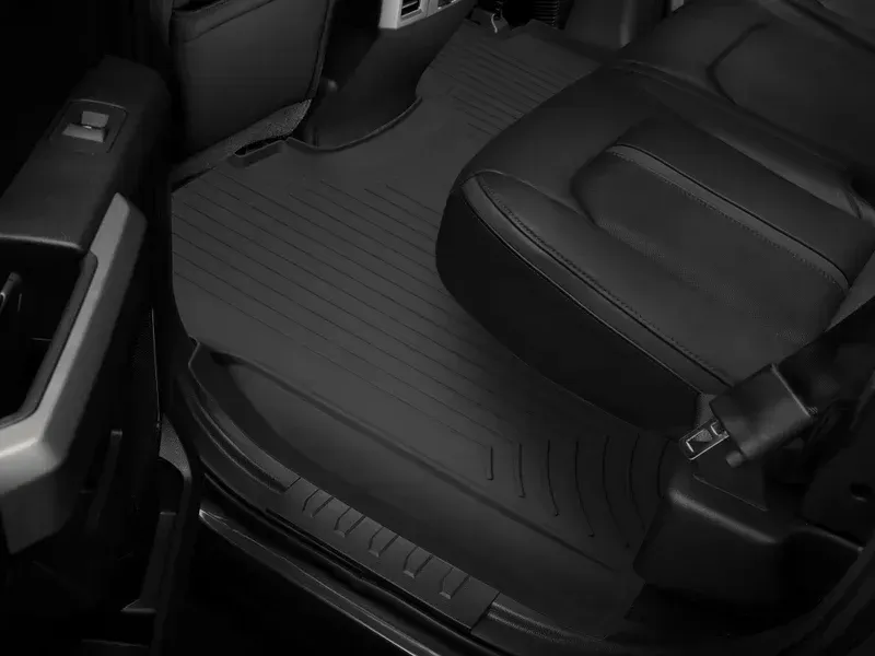 Close-up of a black car back seat with textured floor mat and door panel details