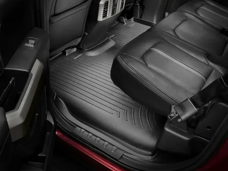 Car interior rear seat area with black leather seats and a ribbed floor mat