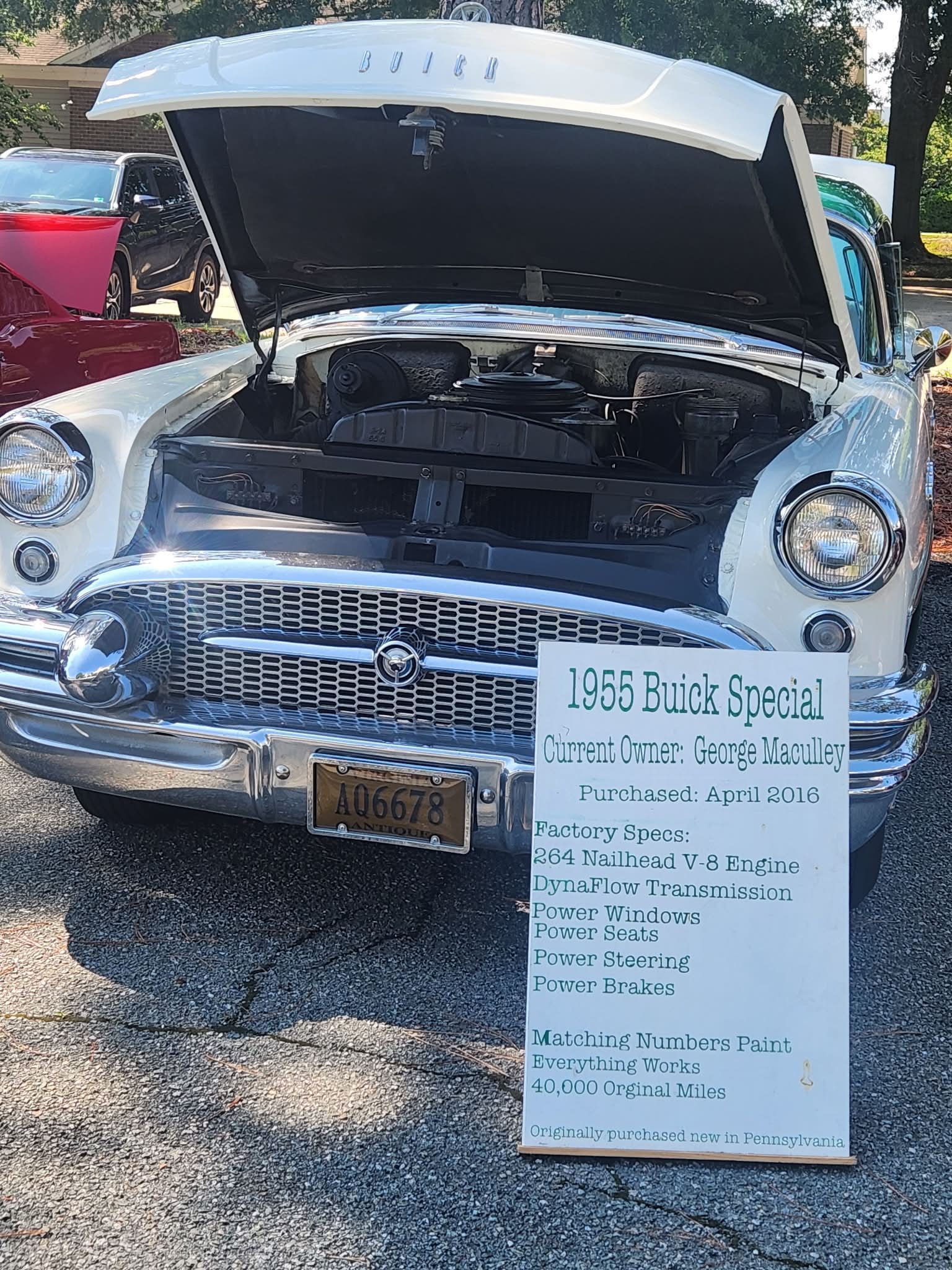 Classic car with open hood and sale sign in front, parked outdoors.