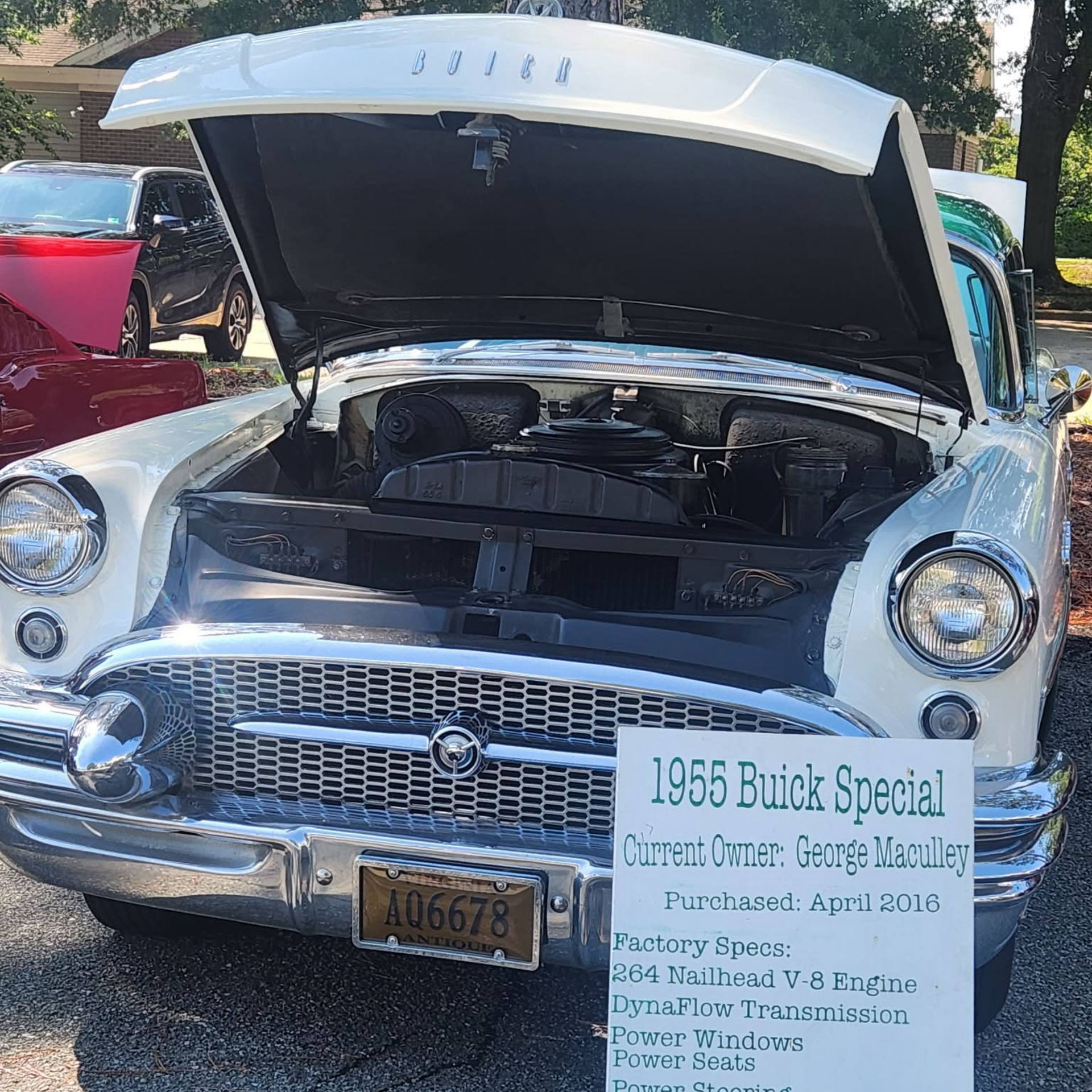 Classic car with open hood and sale sign in front, parked outdoors.